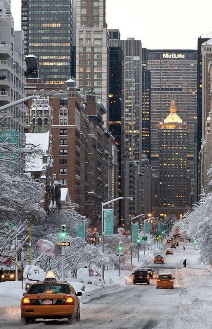 cars driving down a snow covered street in new york city