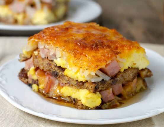 an omelet with meat and cheese is on a plate next to another dish