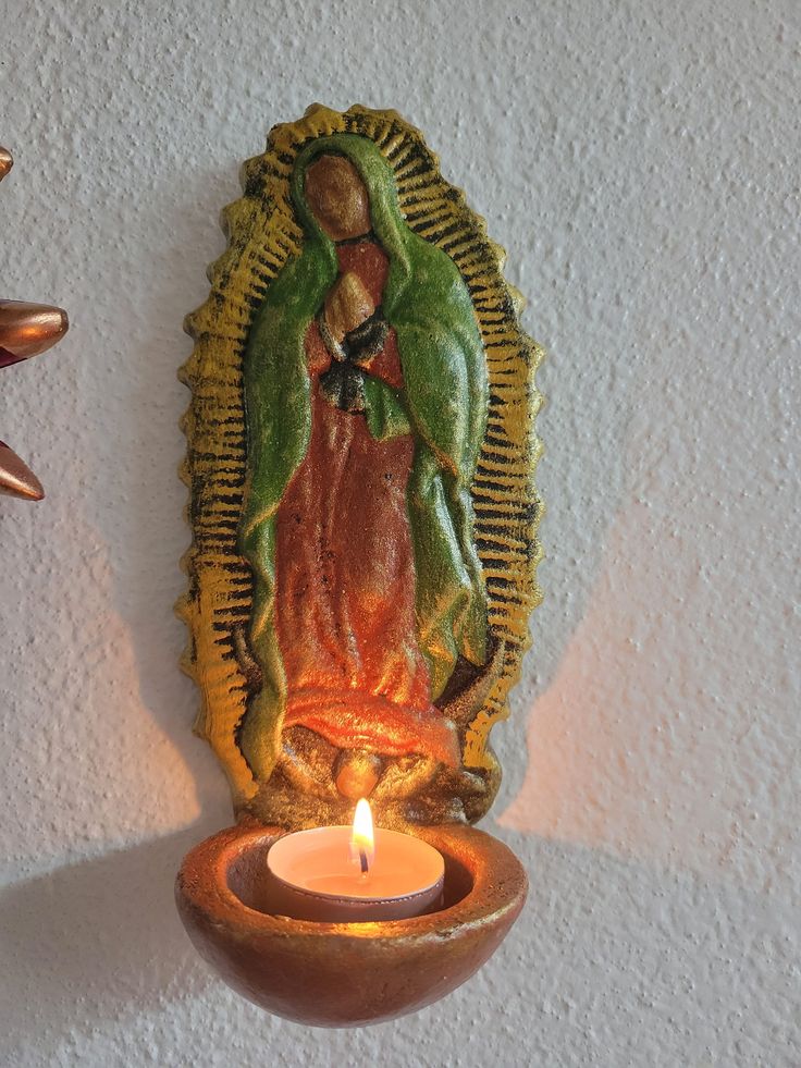 a candle is lit in front of an image of the virgin mary