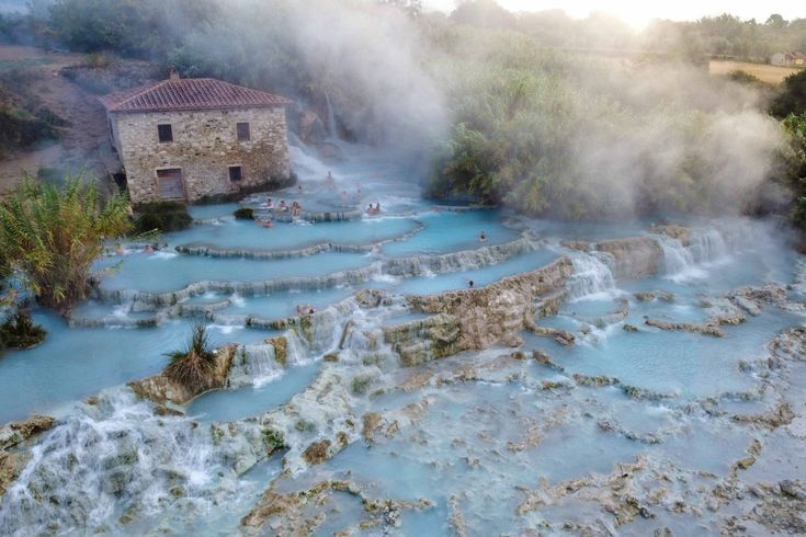 an aerial view of a hot spring with people swimming in it and steam rising from the water