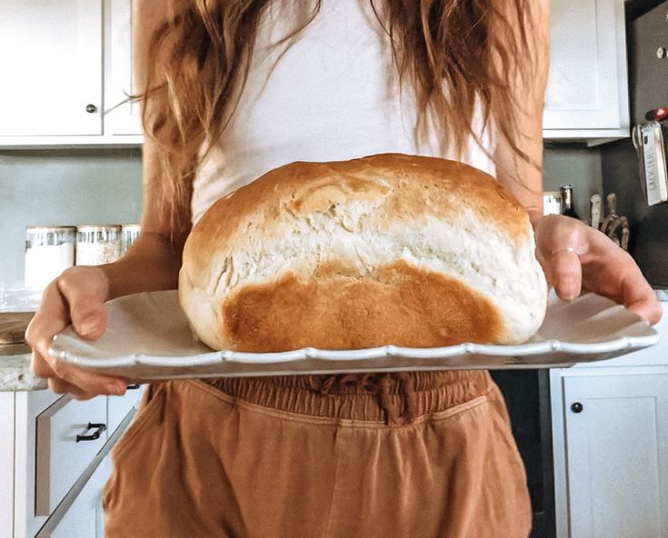 a woman holding a loaf of bread on a tray