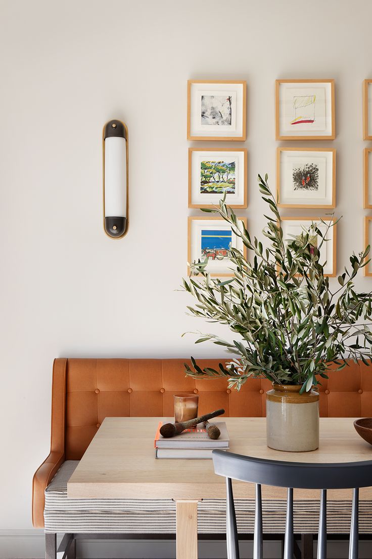 there is a potted plant on the table in front of some pictures and a lamp