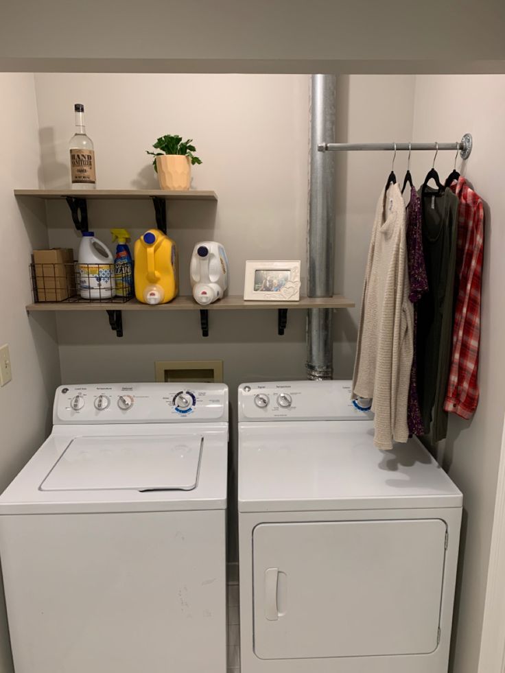 a washer and dryer in a laundry room with clothes hanging on the rack