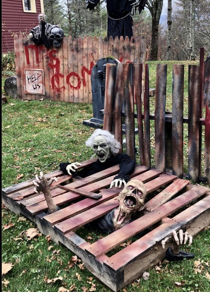 two creepy dolls sitting on top of wooden pallets in the grass next to a fence