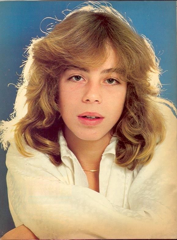 an old photo of a woman with blonde hair and white shirt posing for the camera