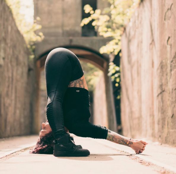 a woman sitting on the ground with her leg up in front of her face and head