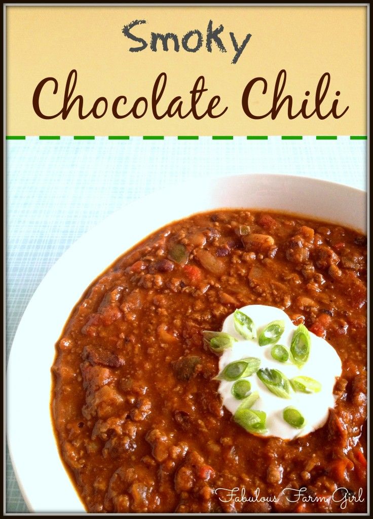 a white bowl filled with chili and sour cream on top of a blue table cloth