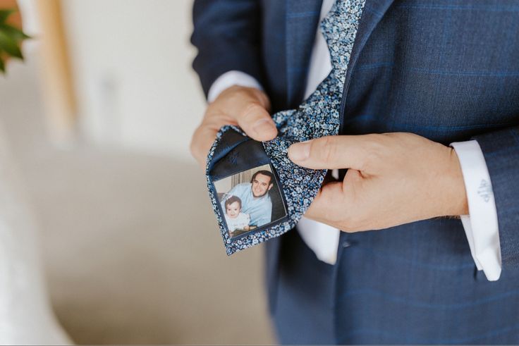 a man in a blue suit is tying his tie with two pictures on it,