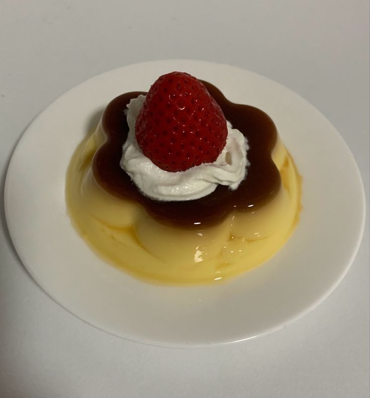 a small dessert on a white plate topped with a strawberry