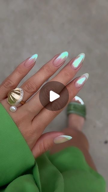 a woman's hand with white and green nail polish on her nails, holding a ring