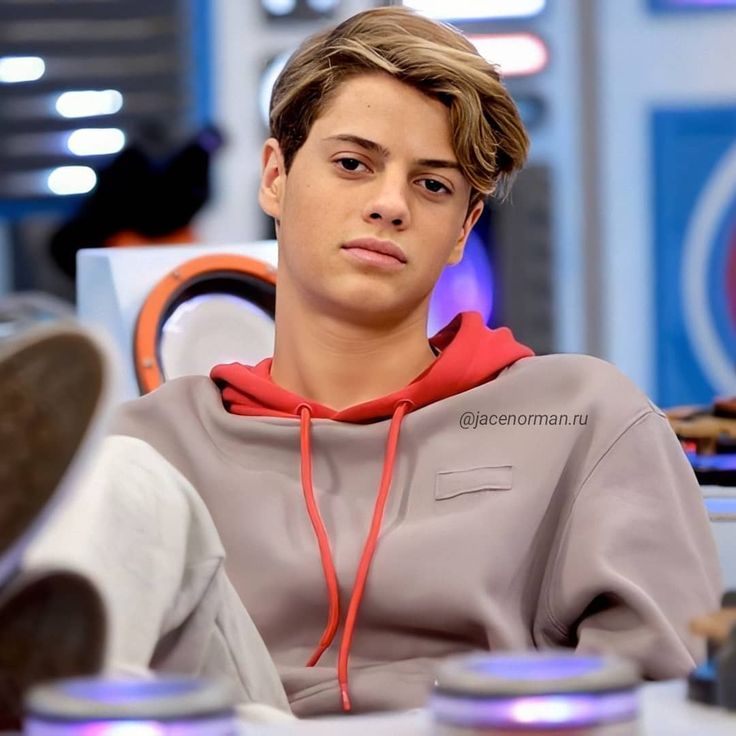 a young man sitting at a desk with his foot on the table and looking off into the distance