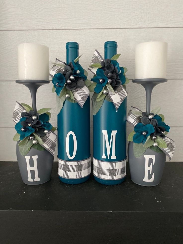 three wine bottles decorated with blue flowers and monogrammed candles