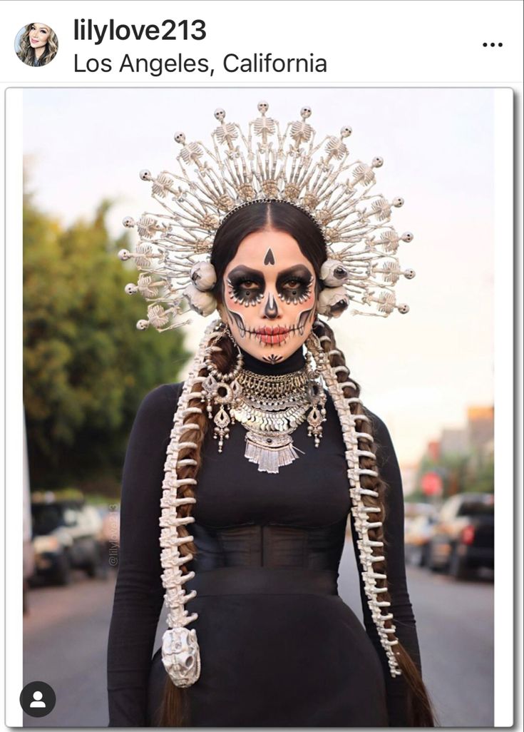 a woman with skeleton makeup and headdress on her face is standing in the street