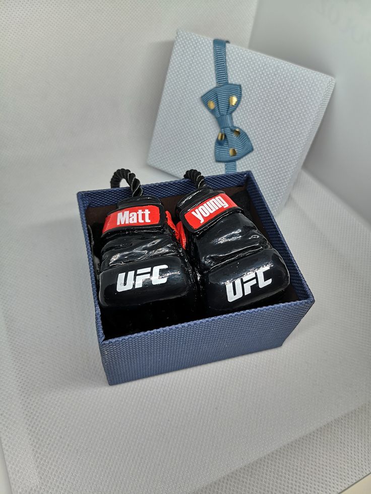 two pairs of boxing gloves sitting in a blue box on top of a white table