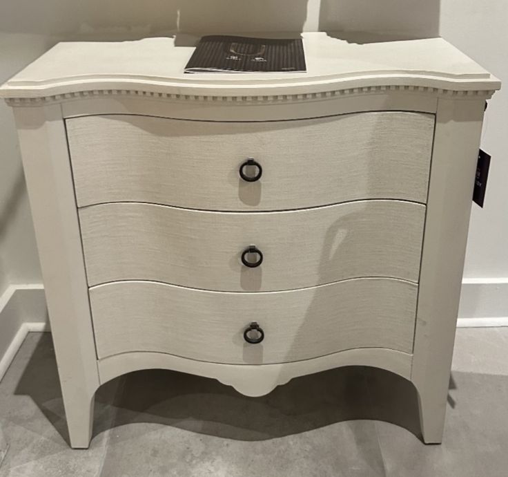 a white dresser with two drawers and a laptop on it's top, in a room