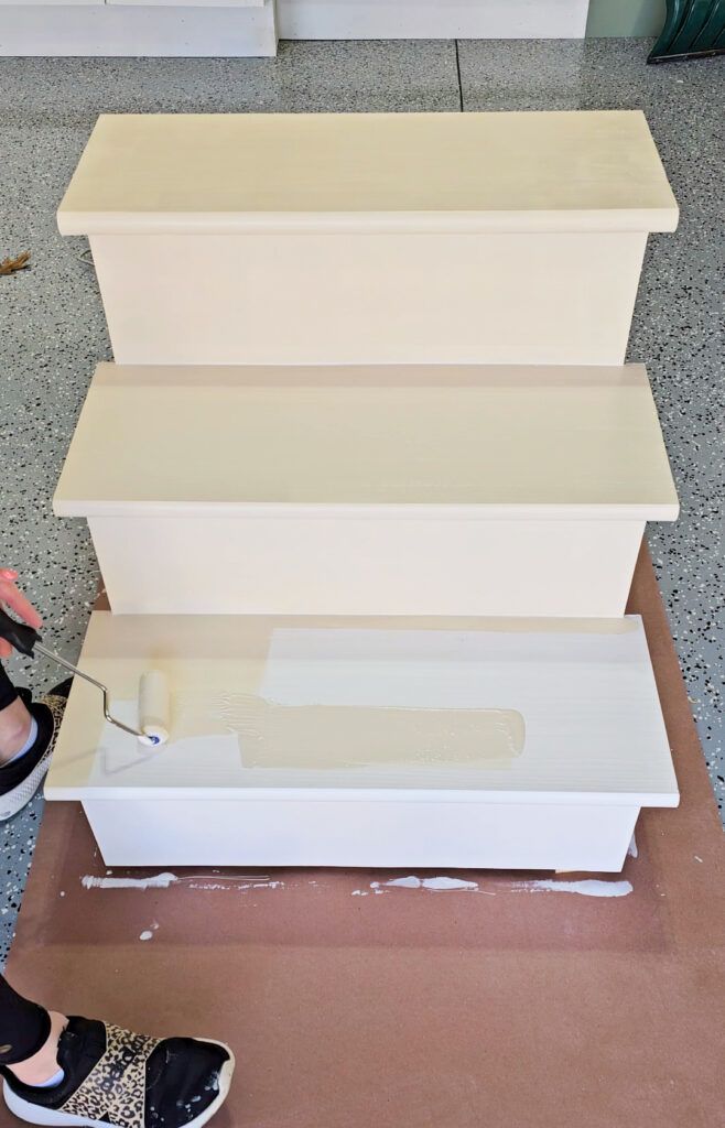 a woman standing next to three white shelves