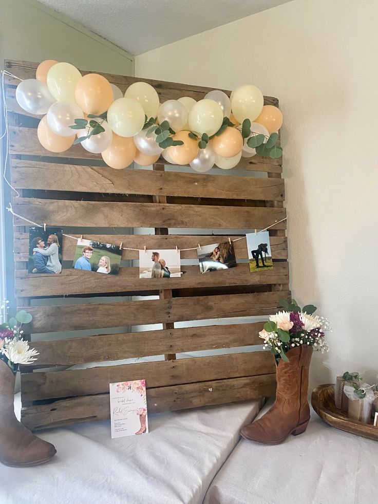 a wooden pallet with balloons attached to it and pictures hanging on the wall above