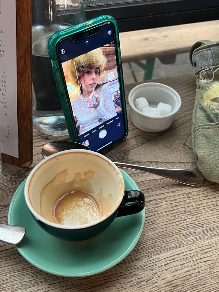 a cup of coffee sitting on top of a saucer next to a cell phone