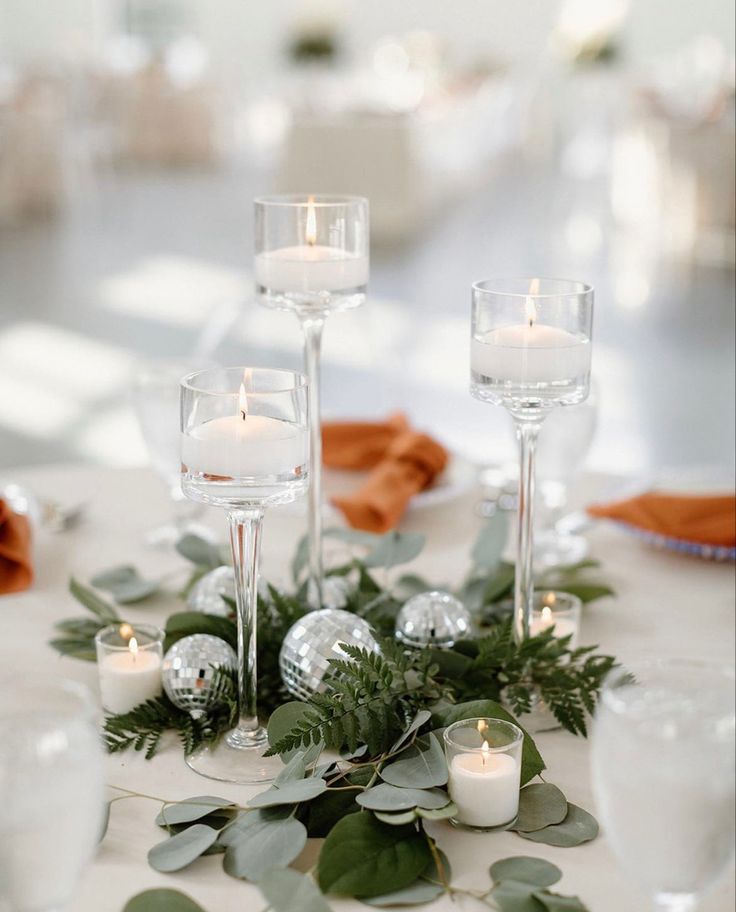 the centerpiece is decorated with greenery and silver baubles as well as candles