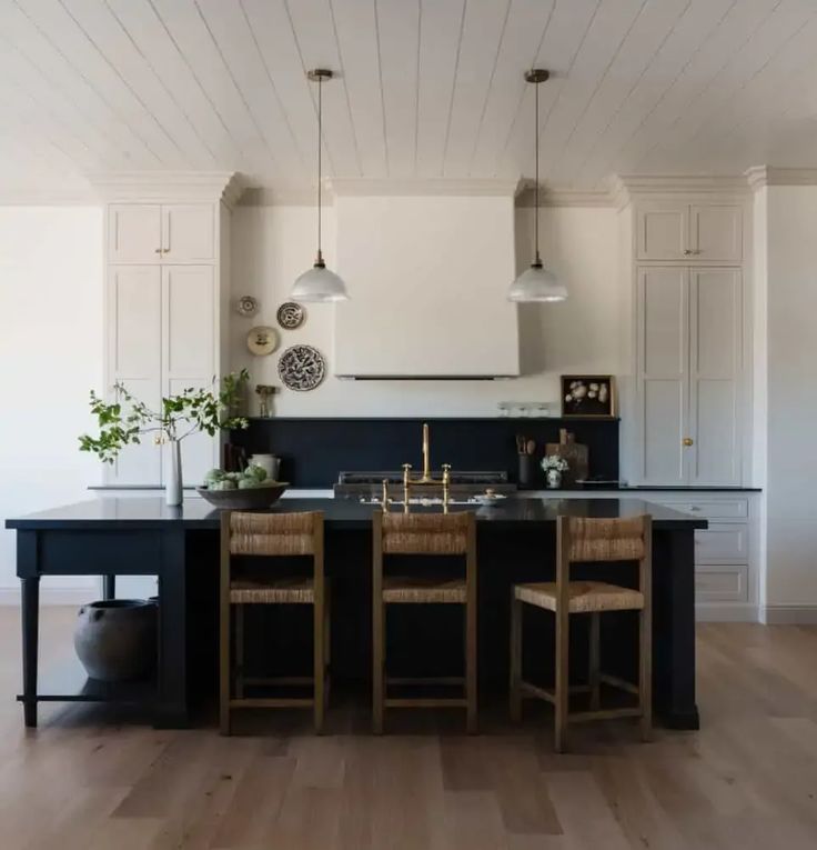 a kitchen with black counter tops and wooden chairs next to an island in the middle