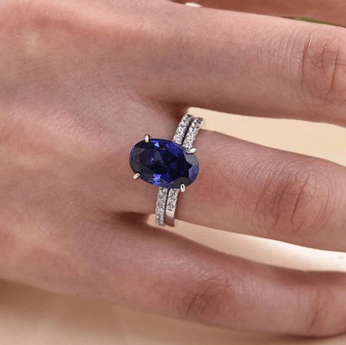 a woman's hand with a ring on it and a blue stone in the middle