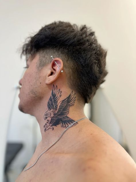 a man with a bird tattoo on his neck and behind his ear, looking at the mirror