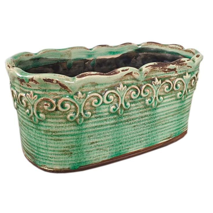 a green and brown planter sitting on top of a white surface with an ornate design