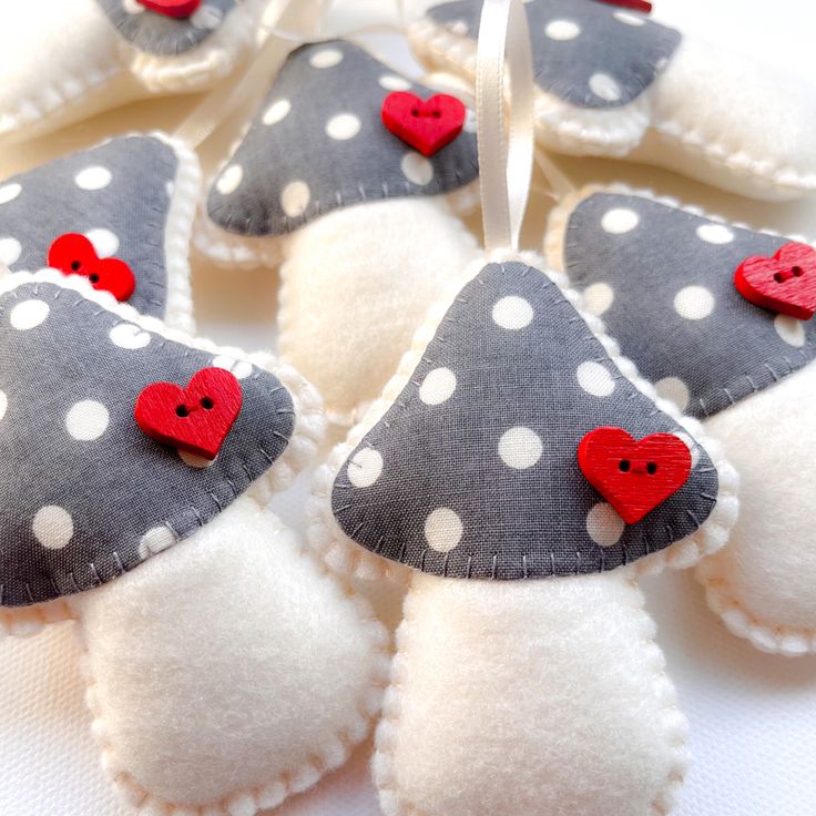 four felt heart ornaments with red and white polka dots are arranged in the shape of hearts