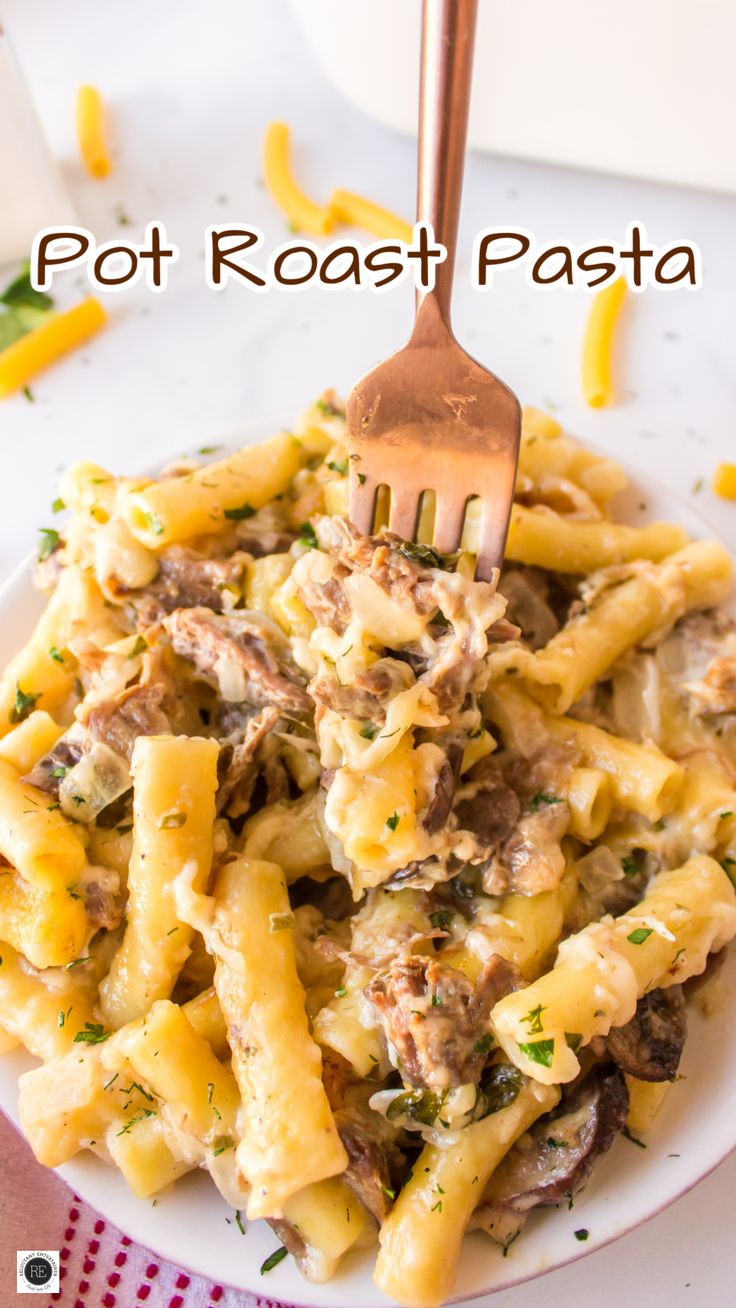 a white plate topped with pasta covered in meat and cheese next to a fork on top of it