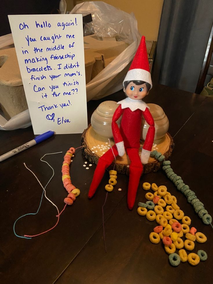 an elf sitting on top of a table next to doughnuts and a note