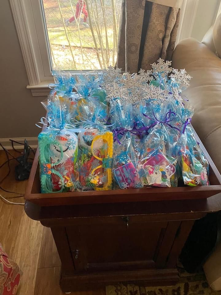 a wooden table topped with lots of bags filled with candy next to a window covered in snowflakes