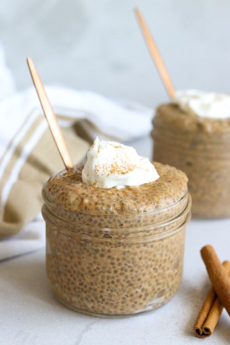 two jars filled with food sitting on top of a white table next to cinnamon sticks