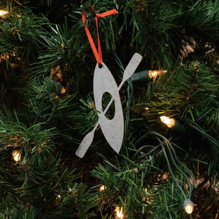 an ornament hanging on a christmas tree with lights in the background and a pair of scissors