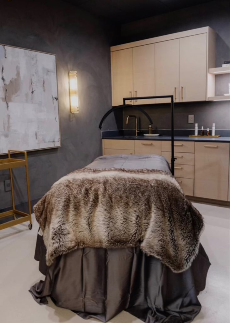 a bed with a fur blanket on top of it in a room next to cabinets