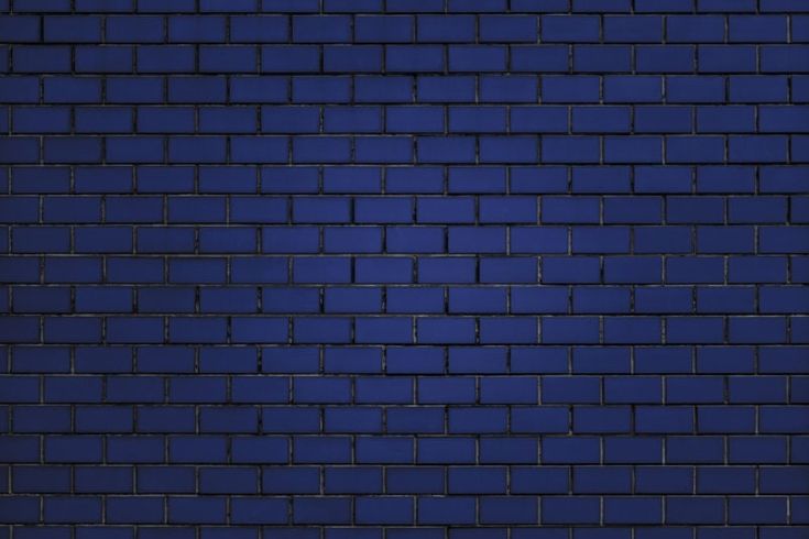 a dark blue brick wall with some light shining on the top and bottom part in the middle