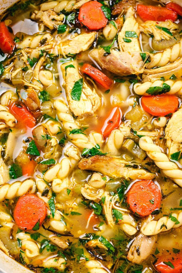 chicken noodle soup with carrots and parsley in a white bowl