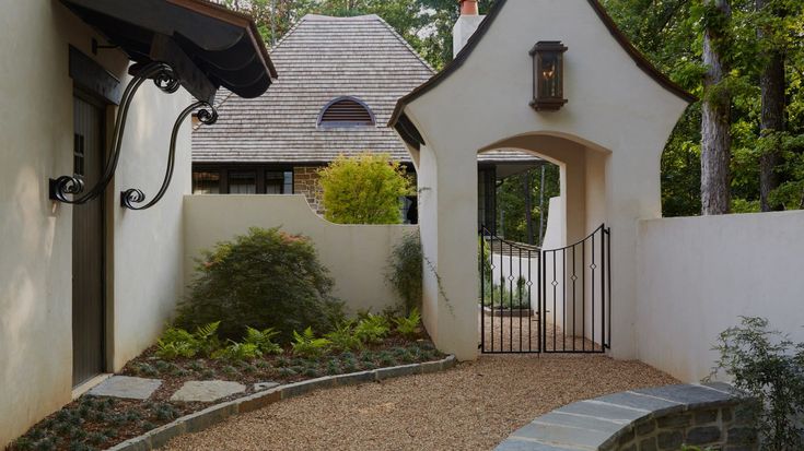 a white house with a black gate in the front yard and walkway leading to it