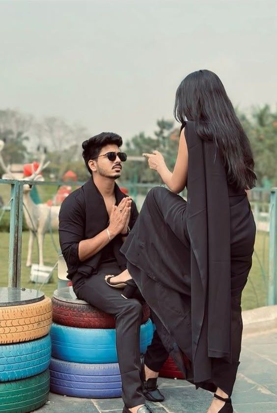 a man and woman sitting on top of colorful tires in front of a park area