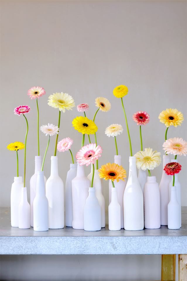 several white vases with different colored flowers in them