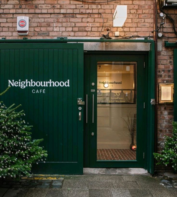 the door to neighborhood care is open on a brick building with green doors and windows