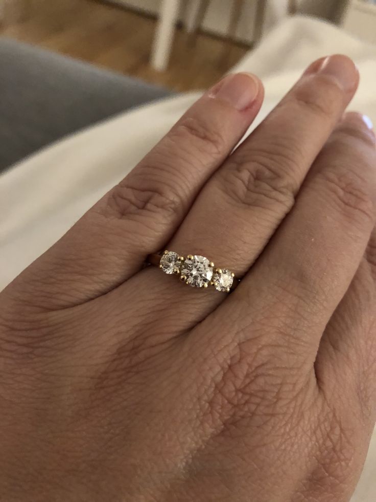 a woman's hand with a three stone ring on it