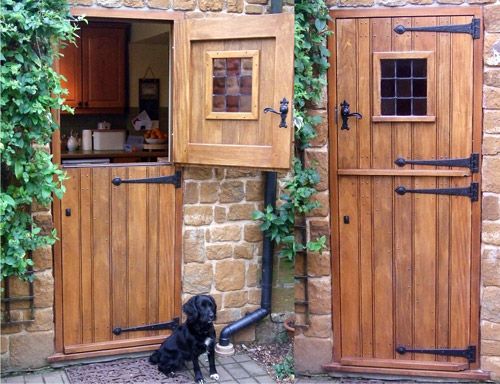 two wooden doors are open on the side of a brick building with ivy growing around them