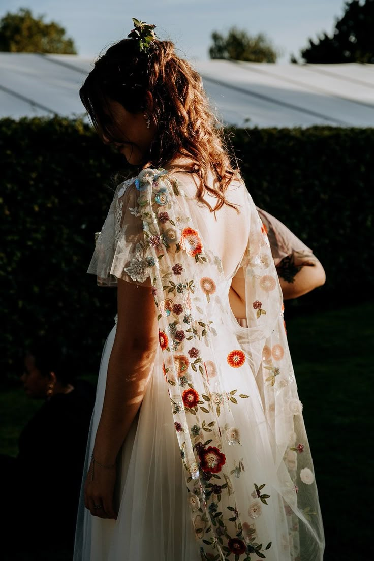 a woman wearing a white dress with flowers on it