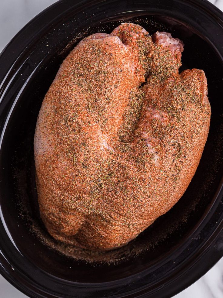 two loaves of bread in a crockpot with seasoning on top, ready to be cooked