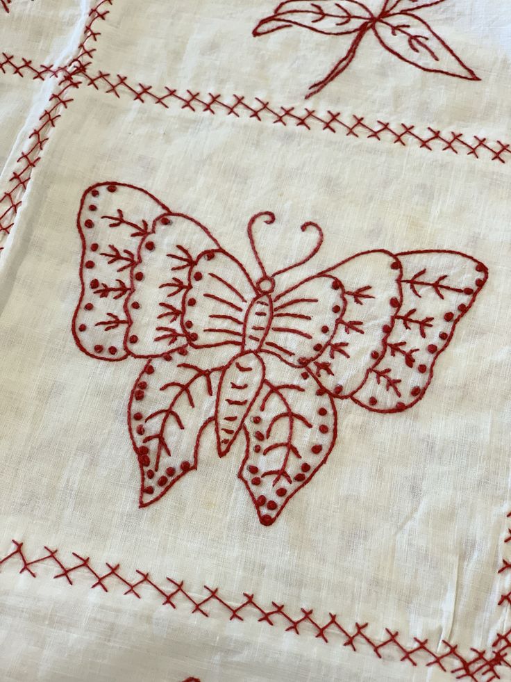 two red embroidered butterflies on white linens with cross - stitched stitches and crosses