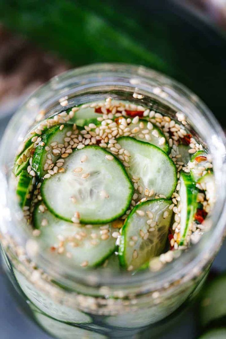 cucumber and sesame seed salad in a mason jar with pickles on top