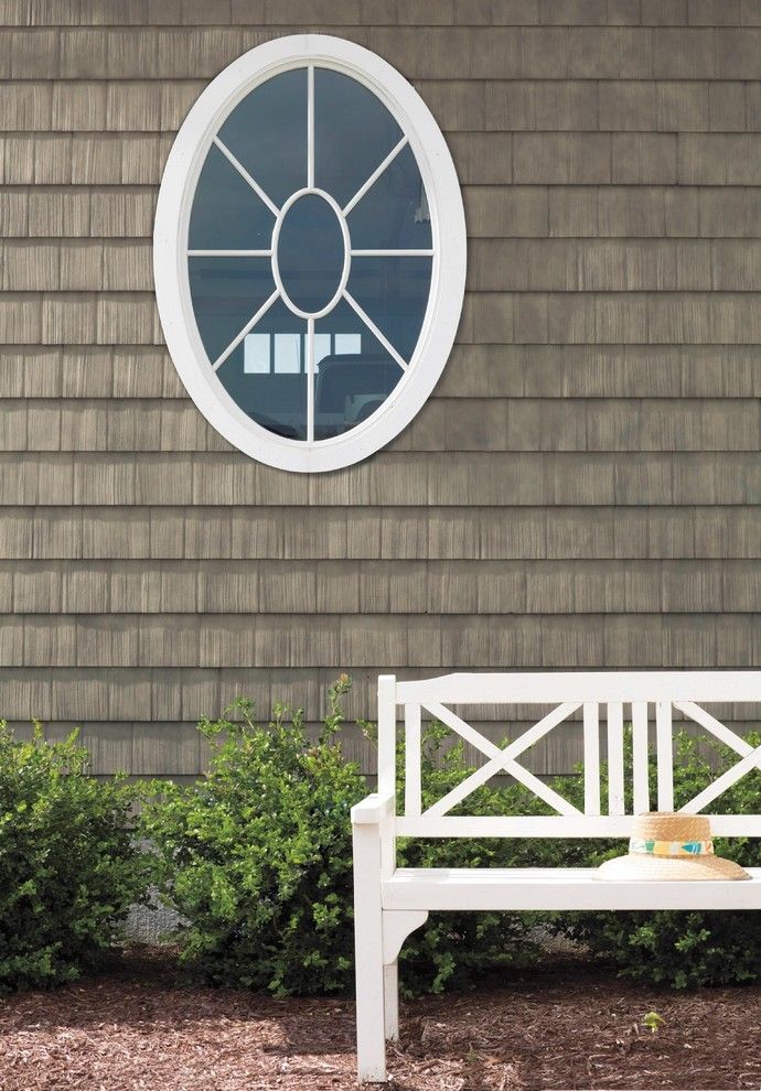 a white bench sitting in front of a house with a round window on the side