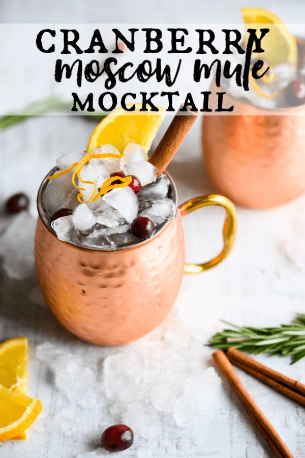 two copper mugs filled with ice, cranberries and cinnamon on top of a table