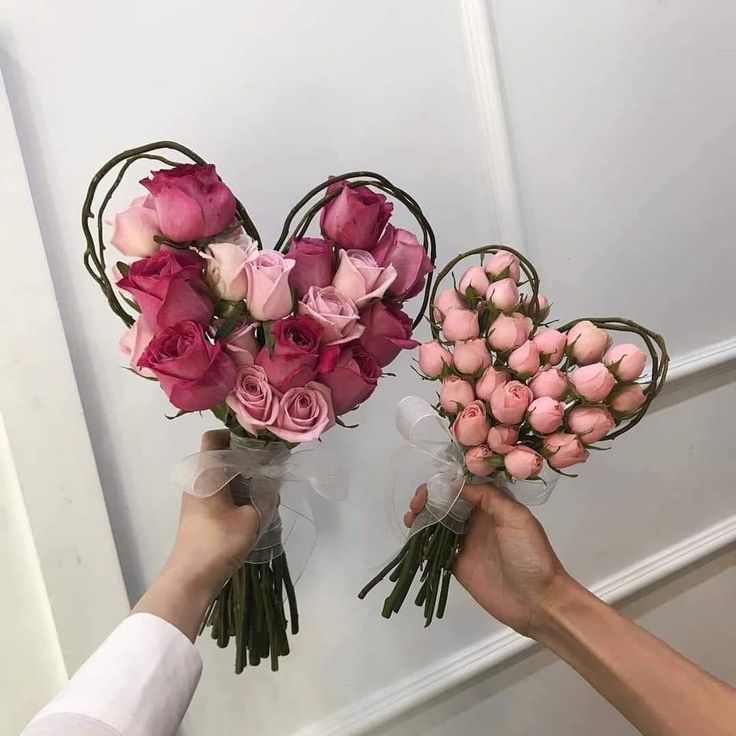 two hands holding pink roses in front of a white door and another person's hand