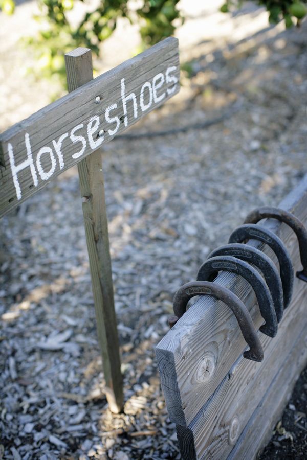 a wooden bench sitting on top of a gravel covered ground next to a sign that says horses shoes